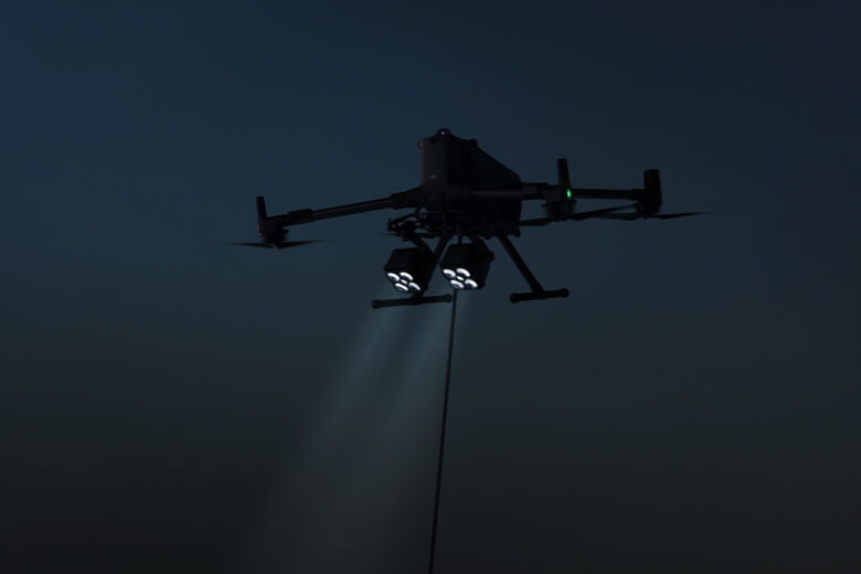 DJI Matrice 350 pilotată noaptea cu două sarcini utile DJI Zenmuse S1 montate care emit fascicule de lumină