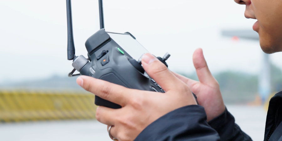 Radiocomanda DJI RC Plus ținută în mâini de un bărbat care vorbește pentru a-și înregistra vocea pe un fundal estompat