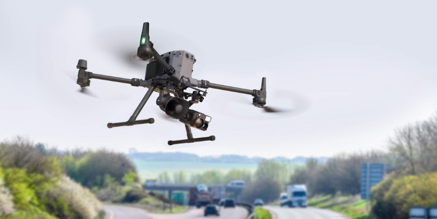 Sarcini utile DJI Zenmuse V1 și DJI Zenmuse H30T montate pe drona DJI Matrice 350 RTK pe o autostradă cu mașini în trecere estompate în fundal